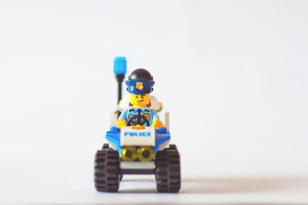 a police LEGO figure riding a toy car symbolizes the idea of exploring alternative solutions before resorting to custom software development